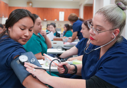 All the students in the medical assistant class are practicing taking blood pressure.