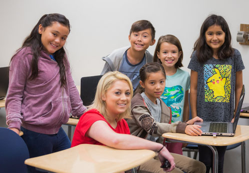 5 children posing and smiling with their computer teacher.