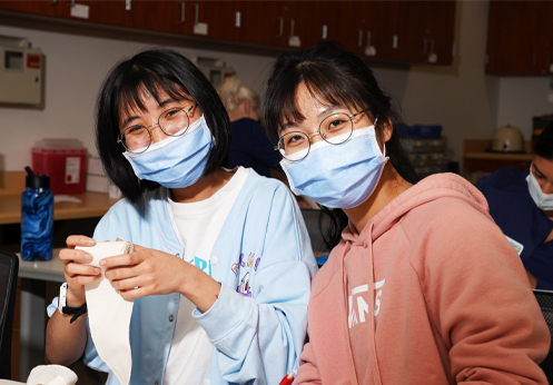 two female students in the medical assistant class undoing medical gauze